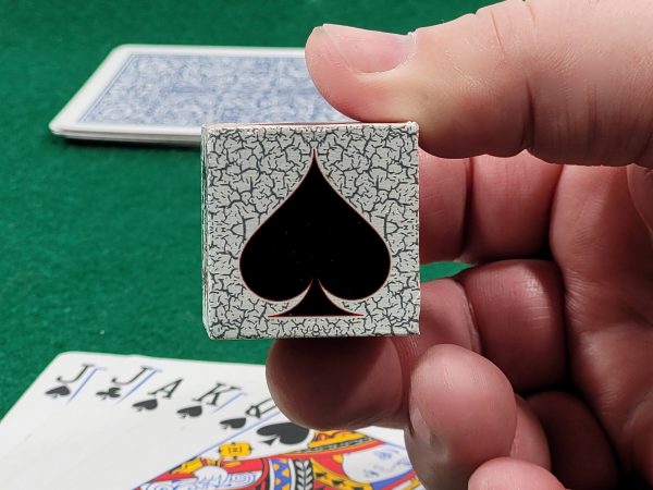Hand showing Vintage Too spade with cards in background