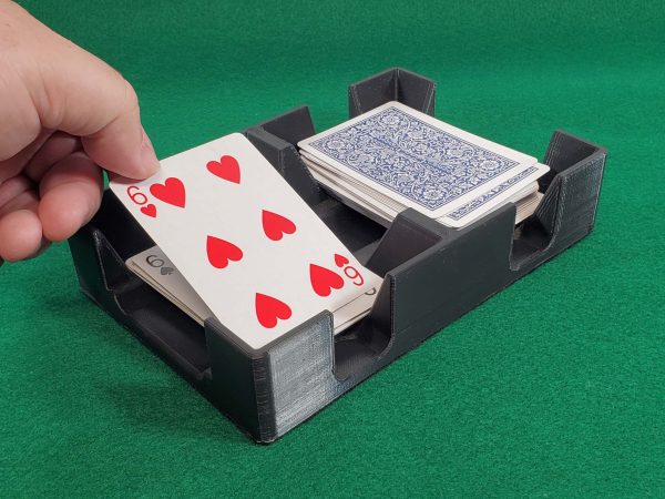Hand picking up 6 of hearts from black card tray
