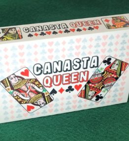 68d5ab538fd207988795859d.jpg Canasta Queen Playing Card Box that features 4 queens from a deck of cards with a backdrop of pips (hearts, clubs, diamonds and spades)